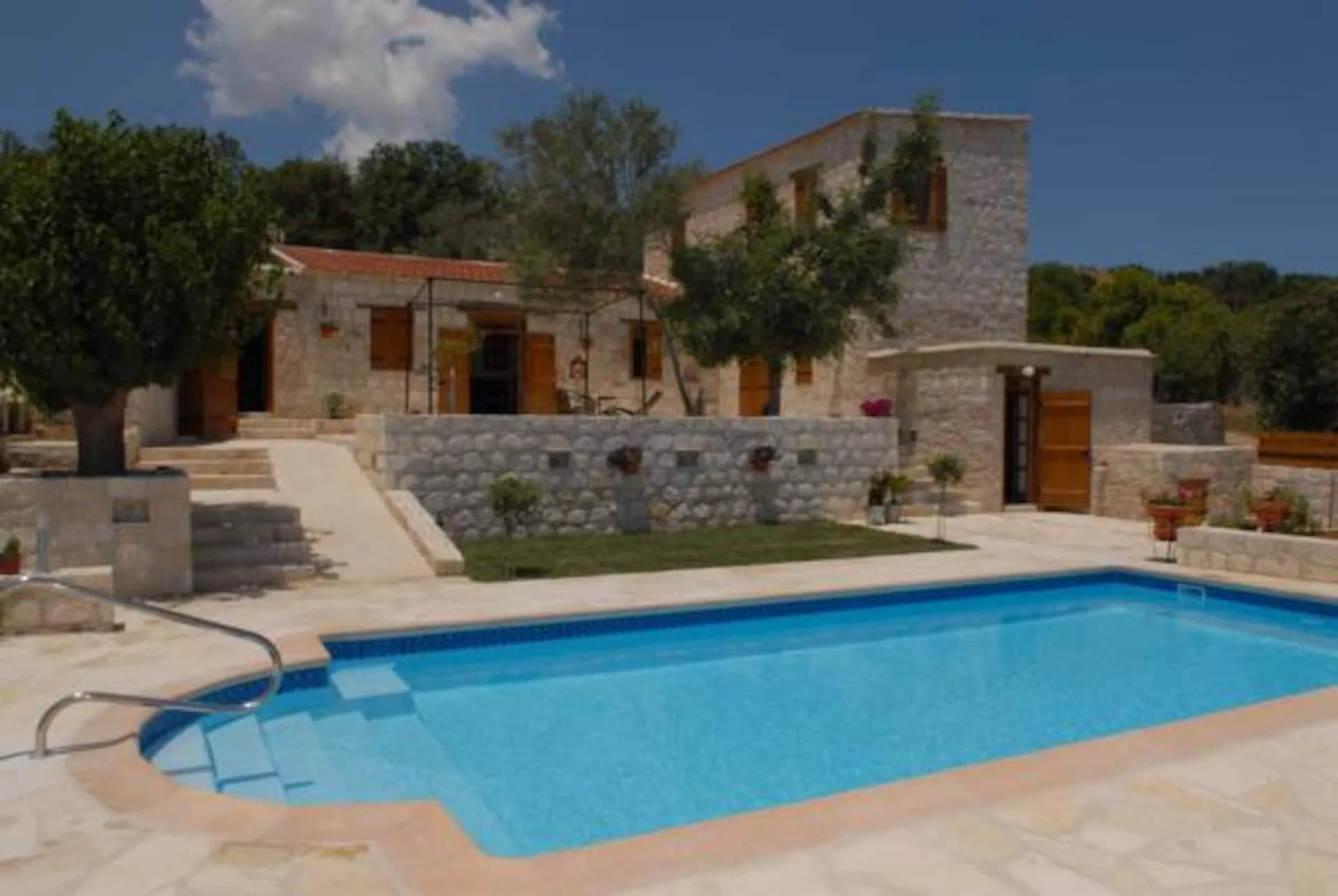 Stone houses with wooden shutters behind the private pool in Kallepeia