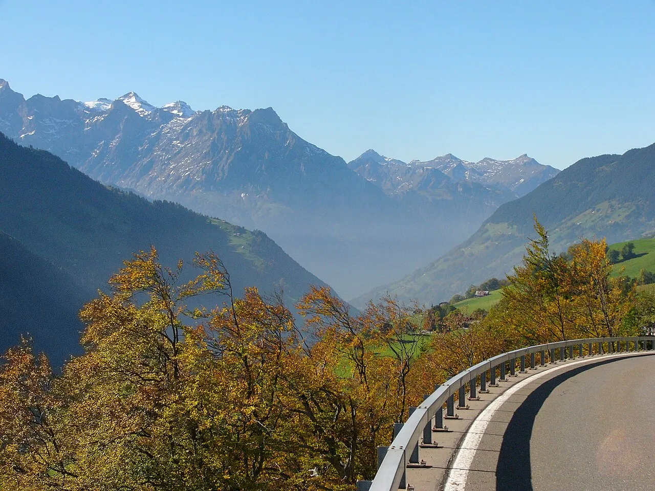 The Klausenpass road curving along a guardrail below snow-dusted peaks
