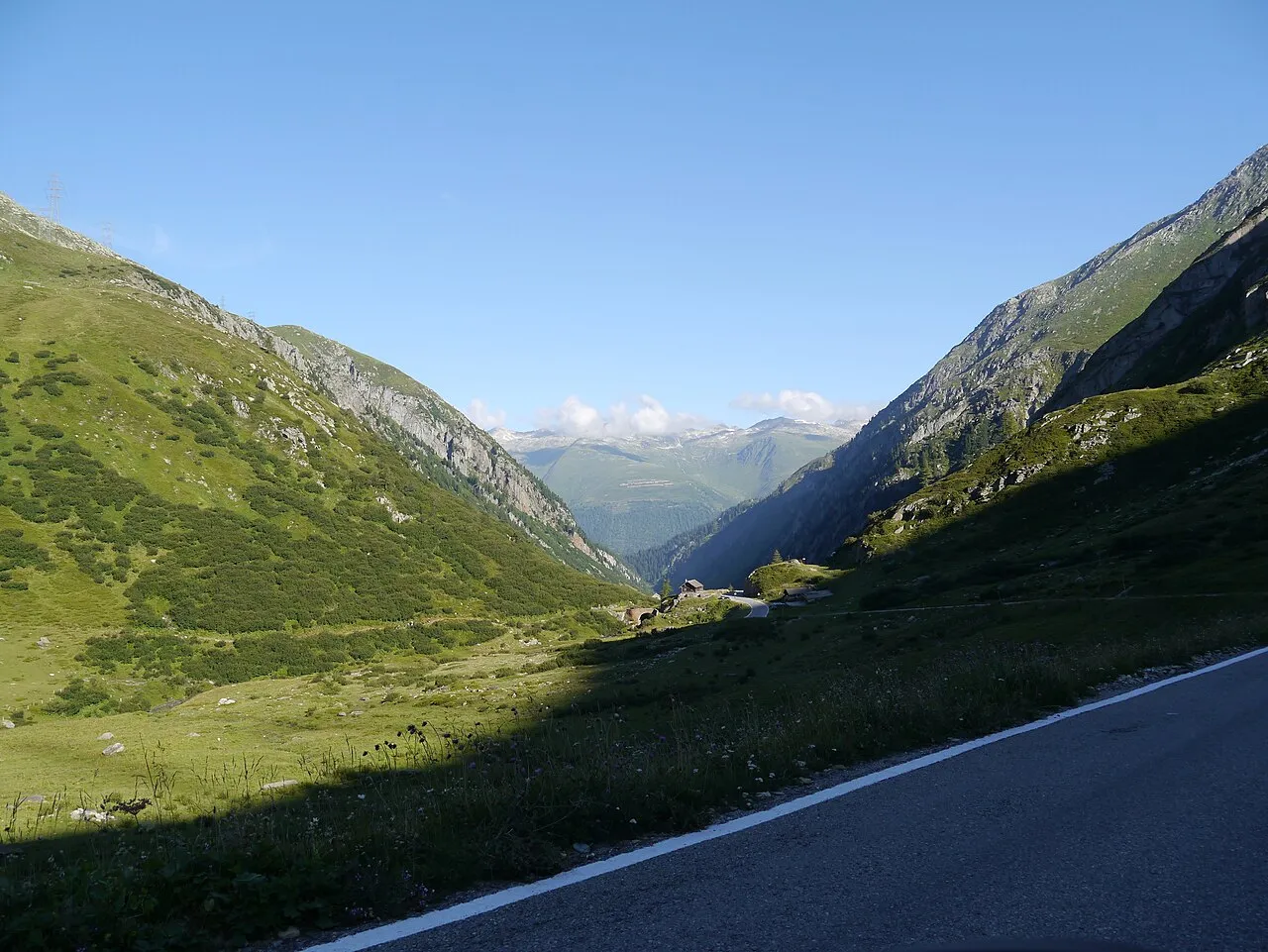 A Valais pass road descending into a green glacial valley